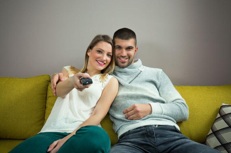 沙发上拿着电视遥控器的情况