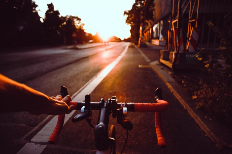夕阳下推着自行车在路边走的人