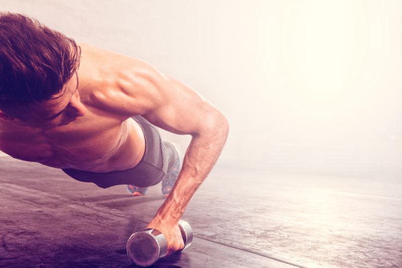 正在拿着哑铃做俯卧撑的男人