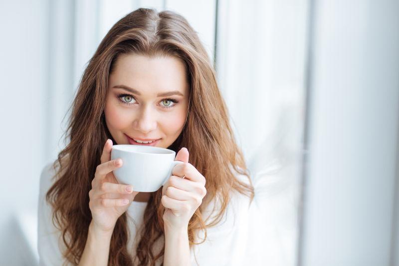 年轻的美女端着杯子喝咖啡