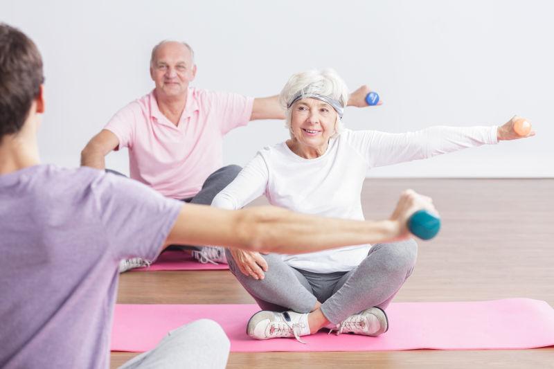 老夫妻坐在瑜伽垫子上健身