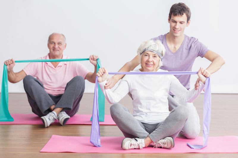 老人拿着丝带健身教练指导