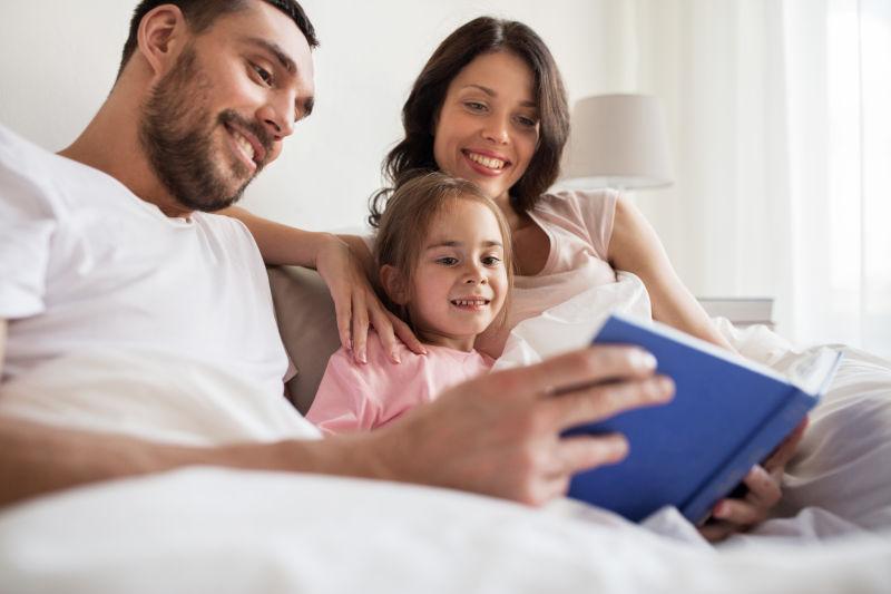 一家三口半躺在床上读书