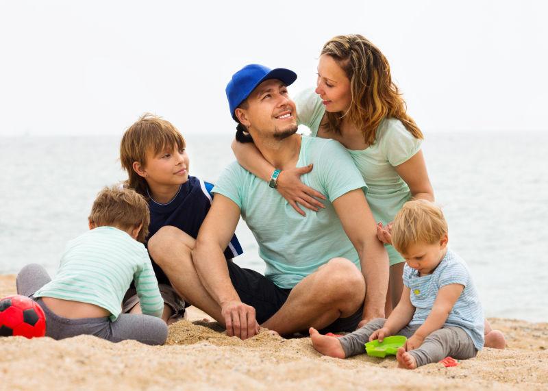带三个孩子的父母在沙滩上休息