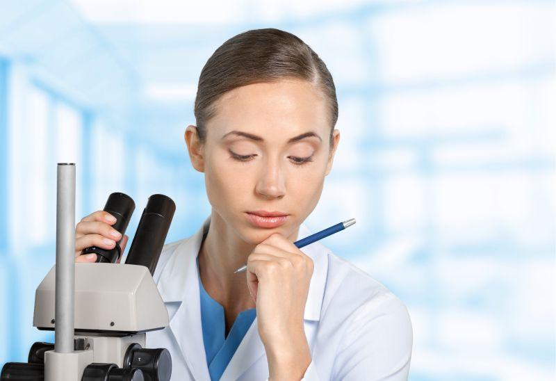 实验室内在显微镜前思考的女研究人员