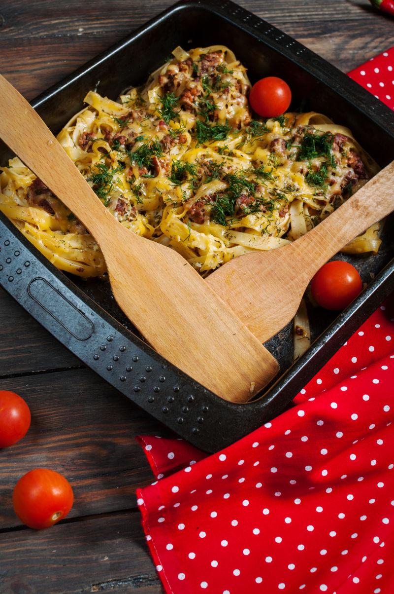 烘焙意大利面配番茄酱和奶酪酱在木桌上