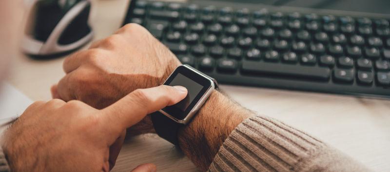 办公桌边男人在检查手上的智能手表