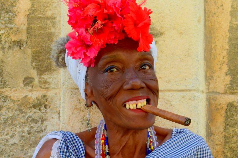 带着花卉帽子的非洲妇女抽着雪茄