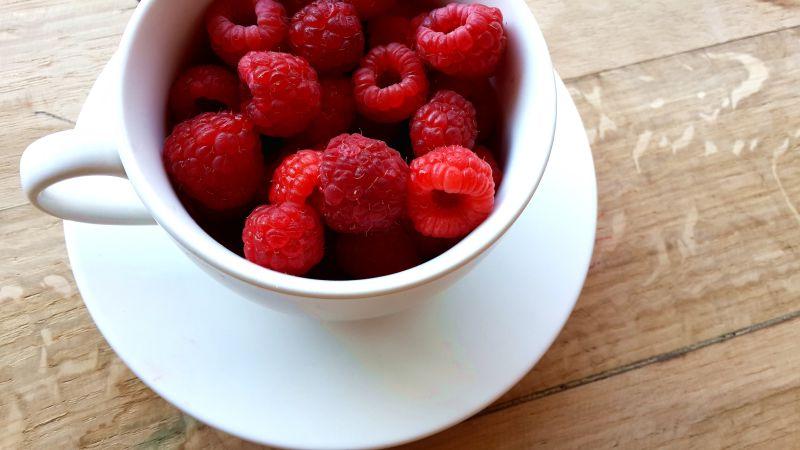 木桌上杯中的覆盆子