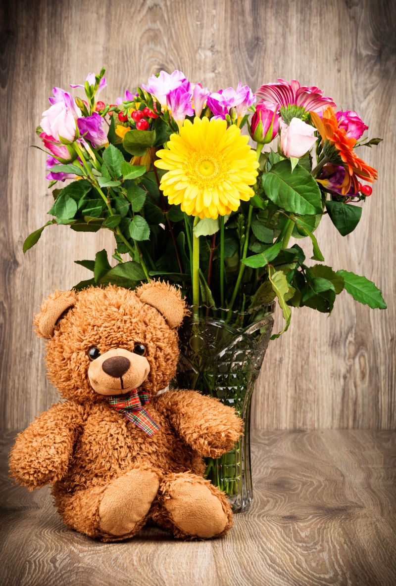 一只泰迪熊和一束鲜艳的花朵