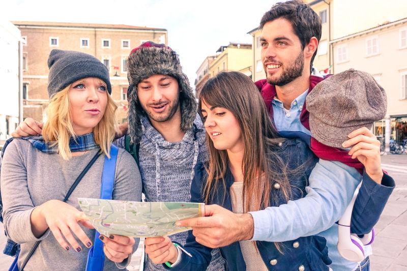 四个旅游的年轻人拿着地图