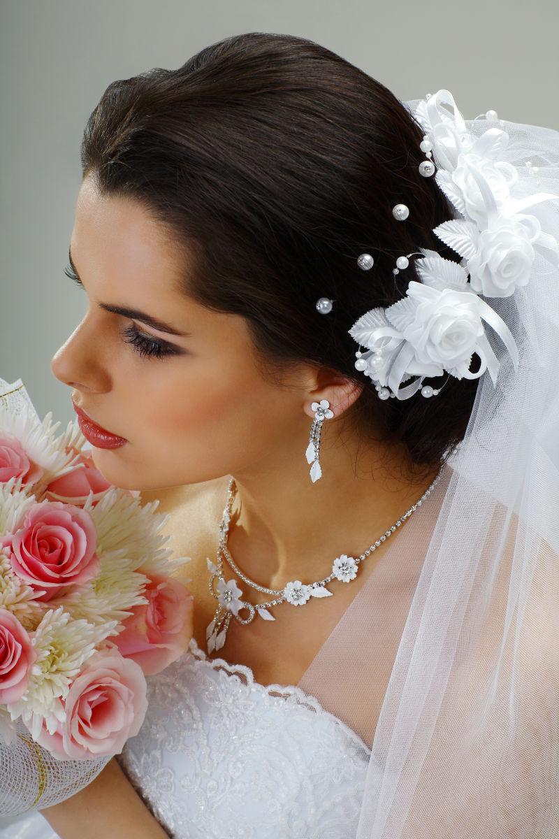 装饰着华丽珠宝的美丽新娘捧着一束鲜花