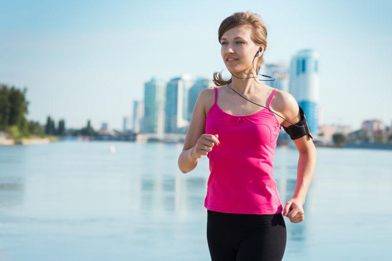 在城里听着音乐跑步的运动妇女