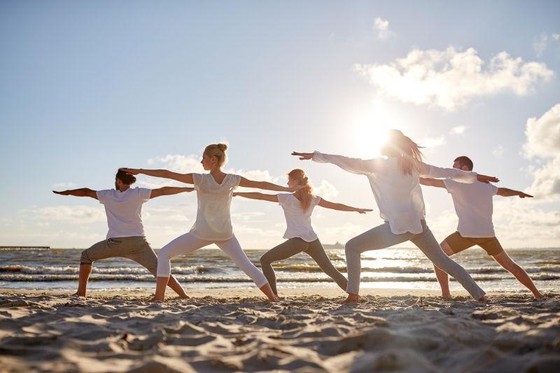 沙滩上练习瑜伽的人们