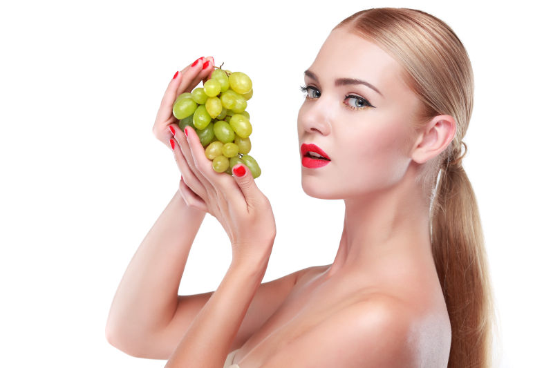 有着时尚妆容的美女拿着葡萄
