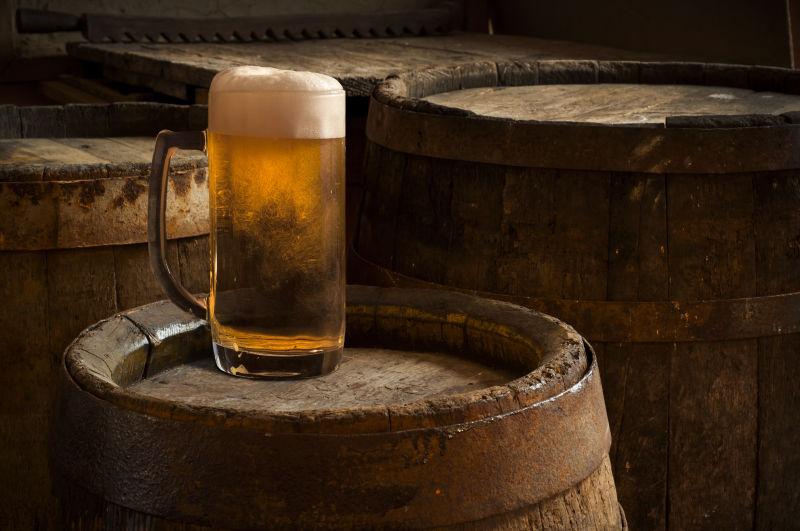 木制背景下酒桶上放着一杯啤酒