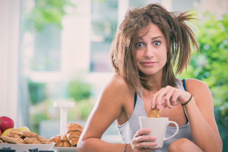 头发凌乱的女人在厨房里吃早餐