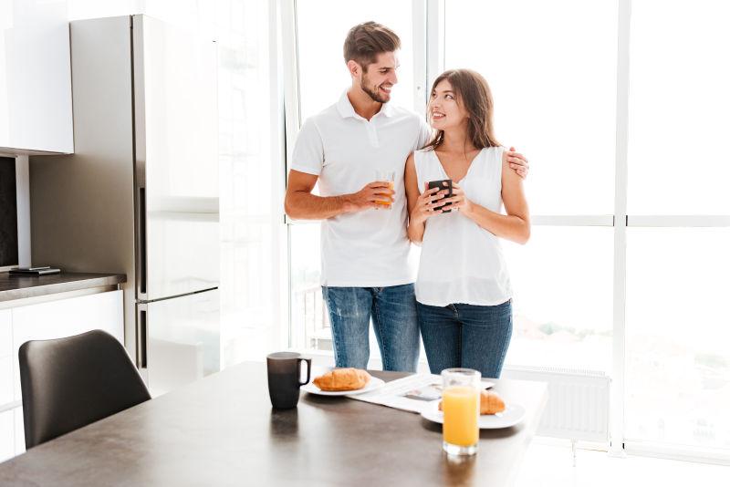 摆着早餐的餐桌前拥抱着的年轻夫妇