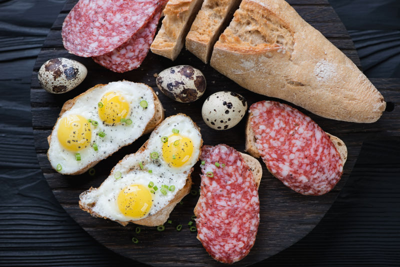 黑色木板上的鹌鹑蛋面包煎蛋和腊肠