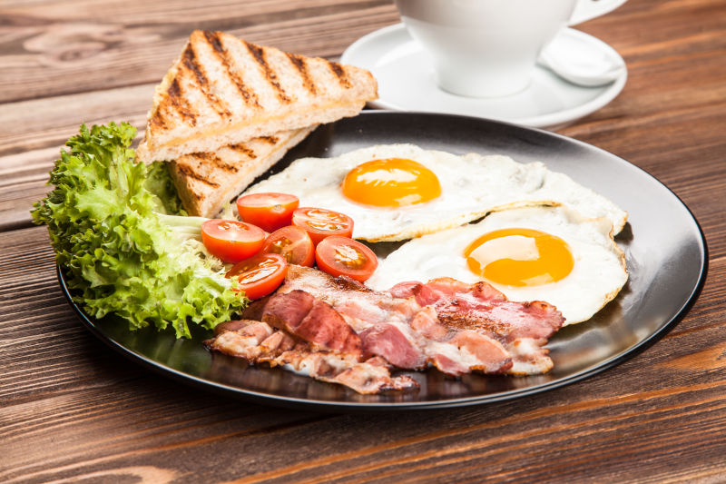 盘子里的荷包蛋熏肉西红柿生菜和烤面包