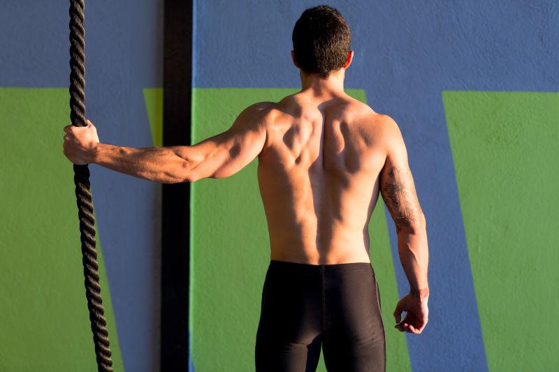 手拉着登山绳的肌肉男背影