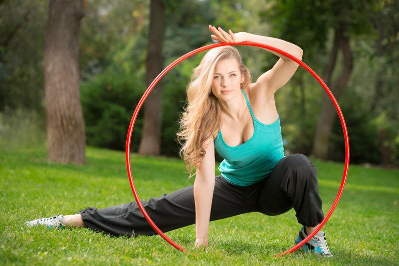 草地上拿着呼啦圈的年轻女运动员