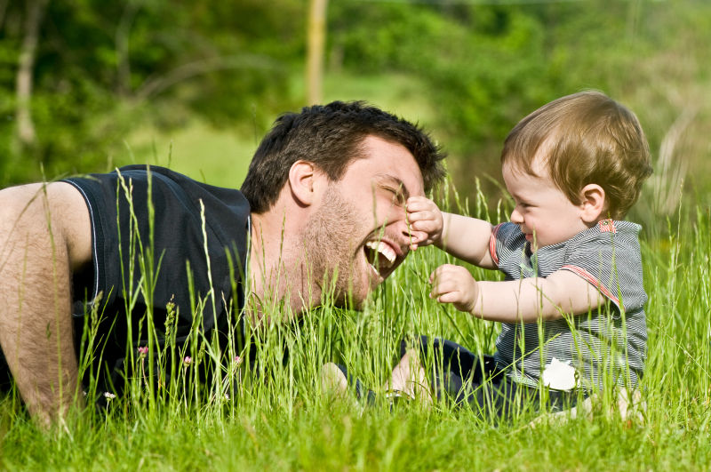 在草地上开心玩耍的父亲和小孩