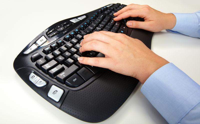 白色桌上在黑色电脑键盘上打字的一双手