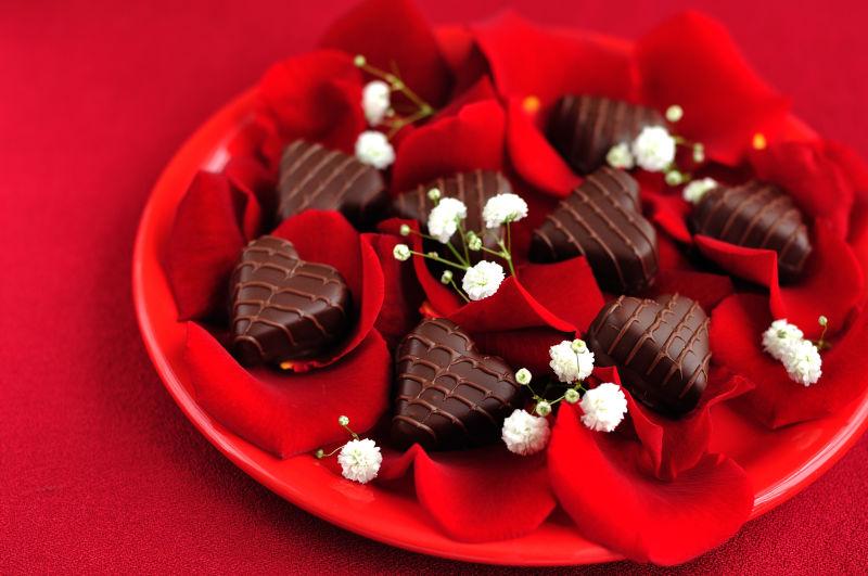 红色托盘里美味的黑色心形巧克力