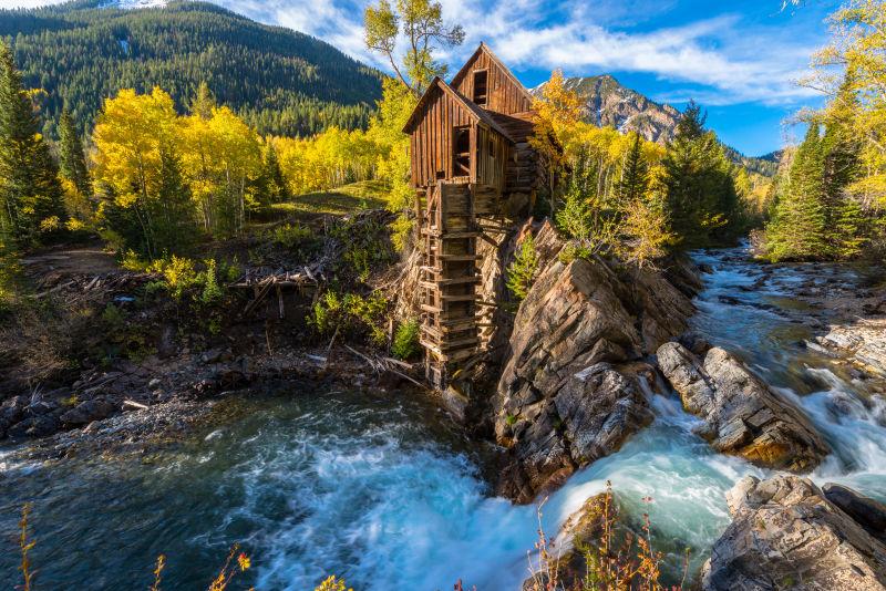 秋季河流岩石上的小木屋