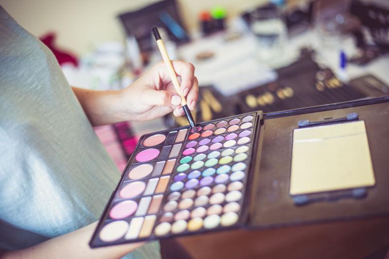 拿着化彩妆的托盘的化妆师