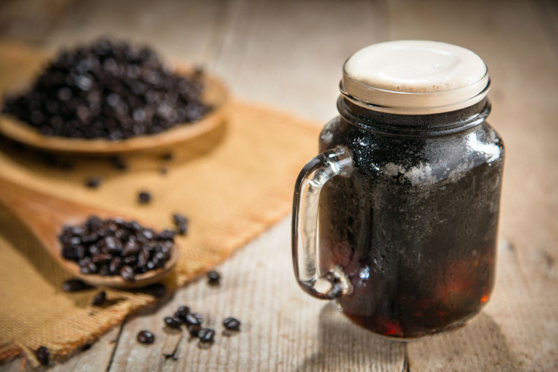 玻璃杯里的咖啡和散落的咖啡豆