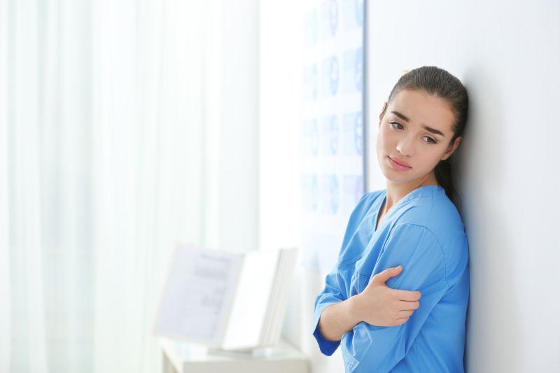 靠在白色墙面上的美女医务人员