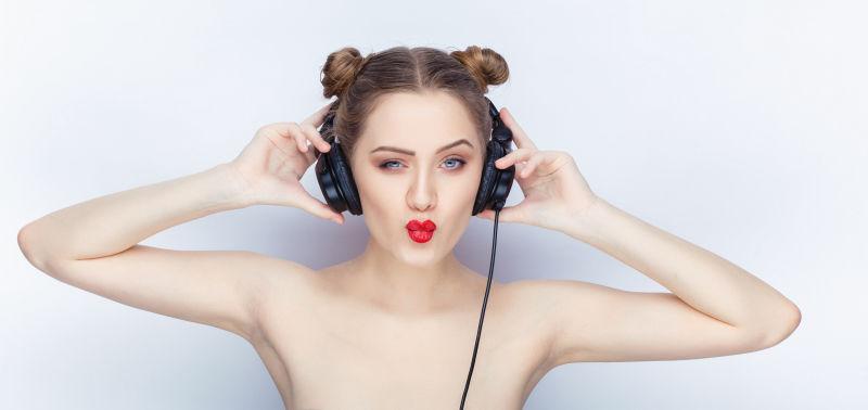 白色背景下裸露肩膀的性感美女头戴黑色耳机
