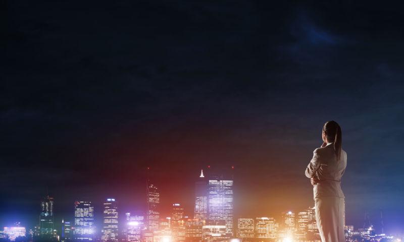 穿着米白职业装的女人看着城市夜景