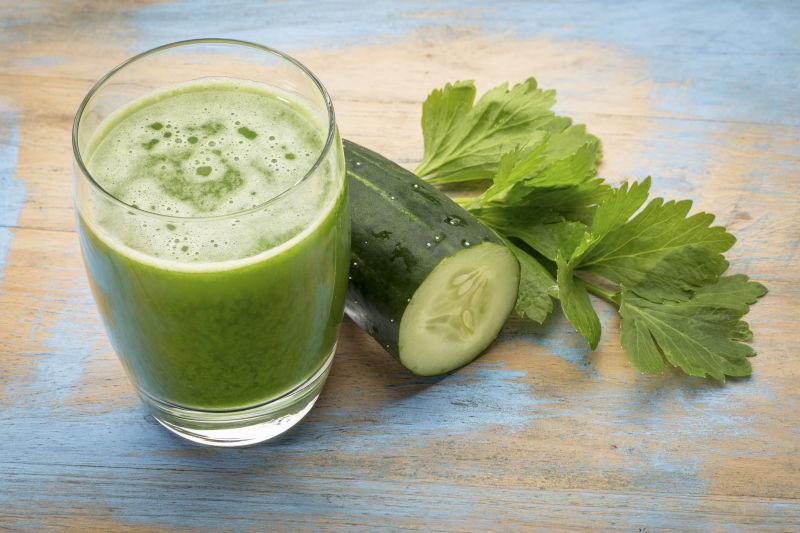 木桌上的新鲜黄瓜和一杯蔬菜汁