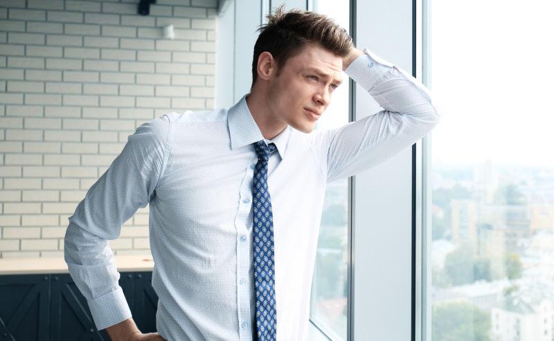 年轻英俊的的商人站在窗边