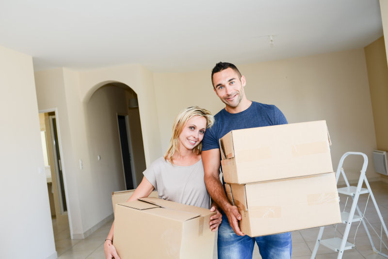 拿着纸箱搬家的情侣