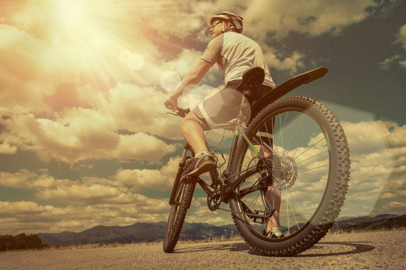 戴着头盔和戴着眼镜的人坐在天空下的自行车上