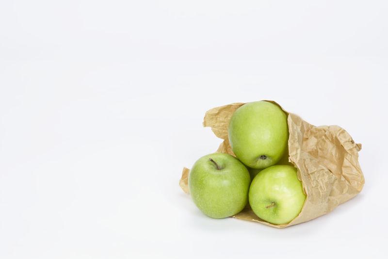 白色背景上装着青苹果的购物纸袋