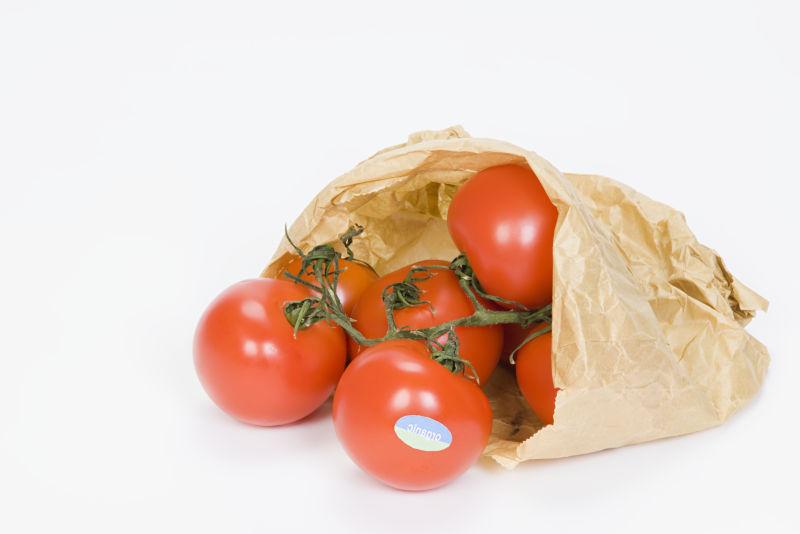 白色背景上装满红色西红柿的购物袋