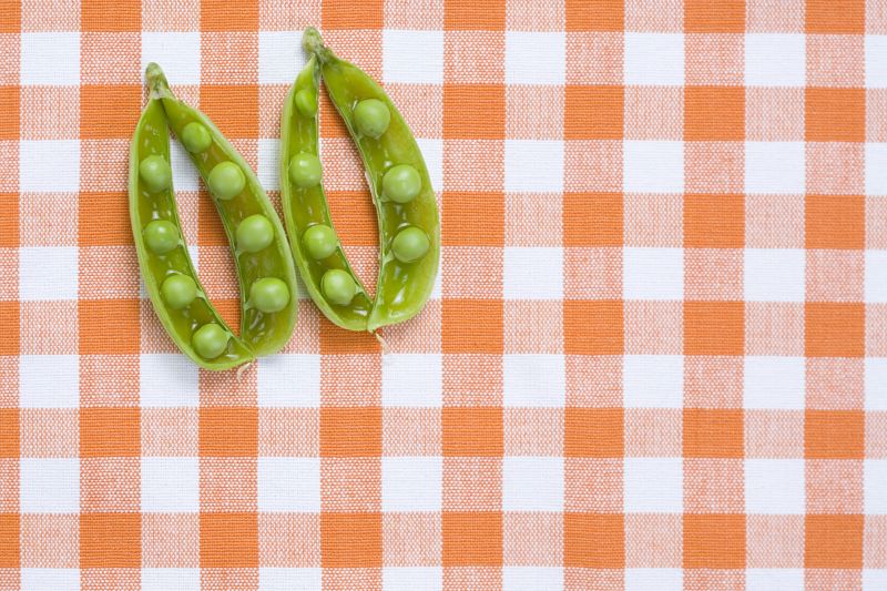橙白色格子背景下的绿色豌豆