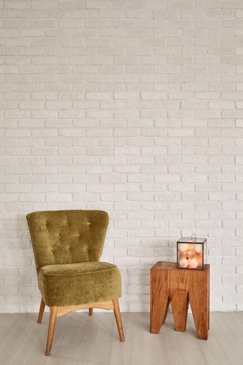 白色砖墙前的绿色扶手椅和小茶几