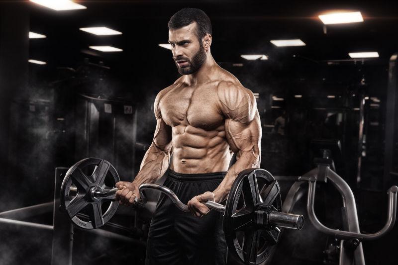 健身房内正在做杠铃练习的男健美运动员
