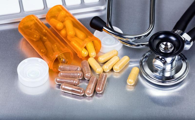 金属背景下的听诊器和药瓶胶囊