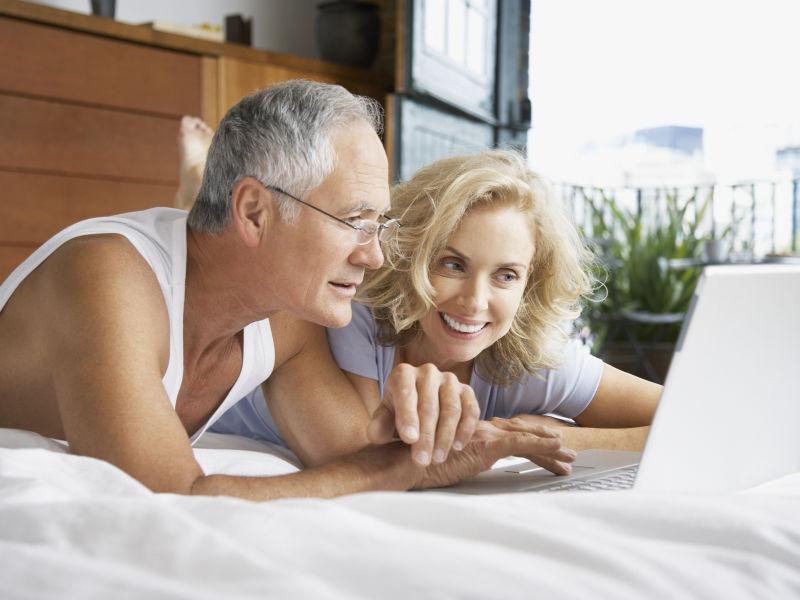 趴在床上看着笔记本电脑的老夫妻