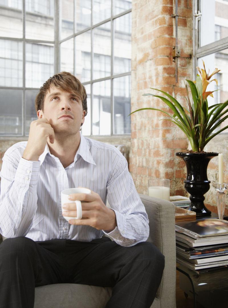 坐在沙发上喝着咖啡的年轻人