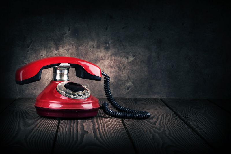 暗背景下木板上的红色复古电话