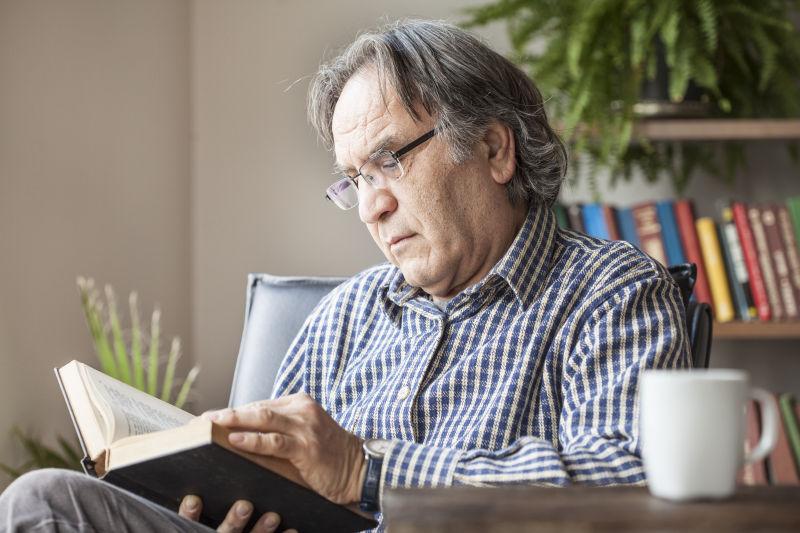 坐在客厅的椅子上看书的老人