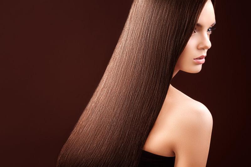 在黑色背景下拥有长长的棕色头发的美女肖像